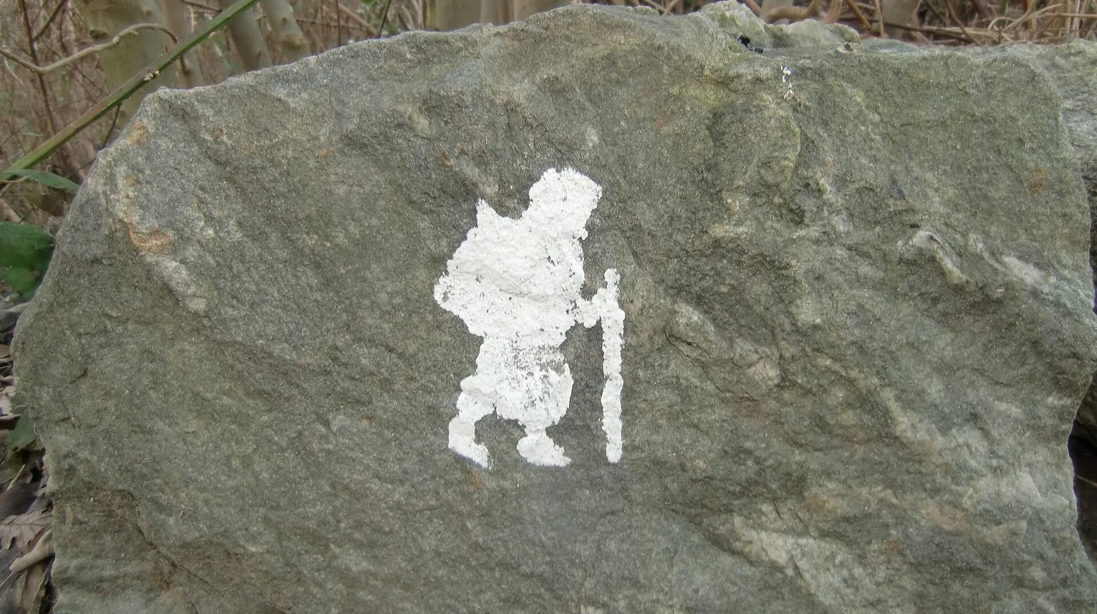 Il simbolo bianco del pellegrino dipinto su una pietra lungo la Via Francigena nel Canavese